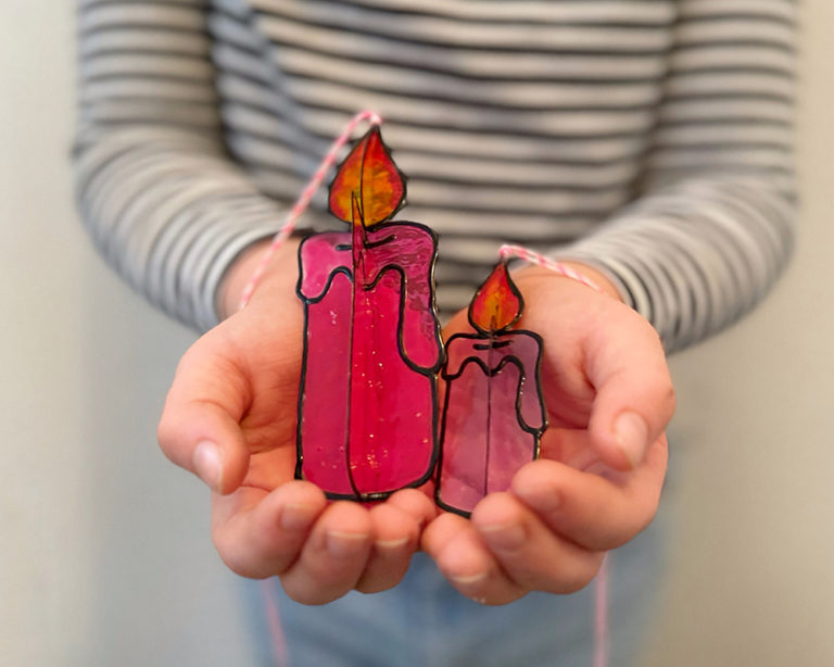 Nagy pink és kisebb lila gyertya tenyérben, fekete kontúrral és lángheggyel